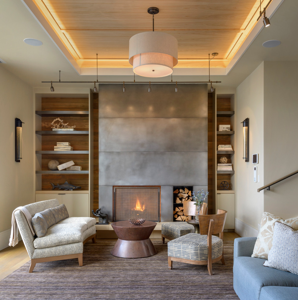 Идея дизайна: гостиная комната в стиле неоклассика (современная классика) с стандартным камином, фасадом камина из металла и синим диваном