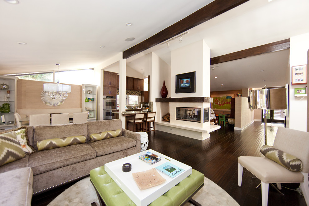 Imagen de sala de estar abierta contemporánea con paredes blancas, suelo de madera oscura y chimenea de doble cara