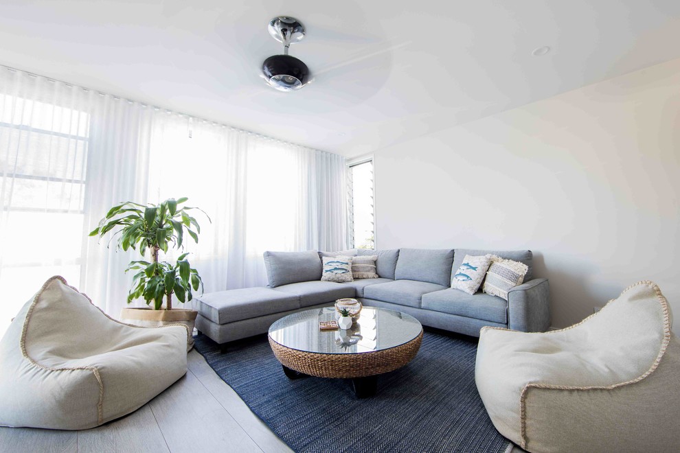 На фото: изолированная гостиная комната среднего размера в морском стиле с белыми стенами, деревянным полом, мультимедийным центром и серым полом