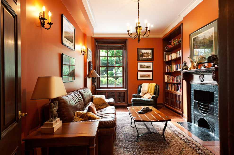 Стильный дизайн: гостиная комната в классическом стиле с с книжными шкафами и полками, оранжевыми стенами и стандартным камином без телевизора - последний тренд