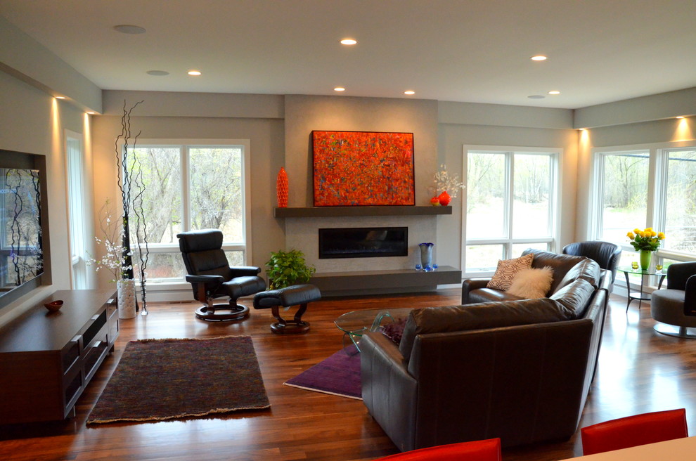 Photo of a contemporary open plan games room in Minneapolis with a plastered fireplace surround, a wall mounted tv, white walls, medium hardwood flooring and a hanging fireplace.