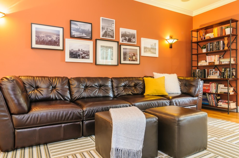 Cette photo montre une salle de séjour chic avec un mur orange et un sol en bois brun.