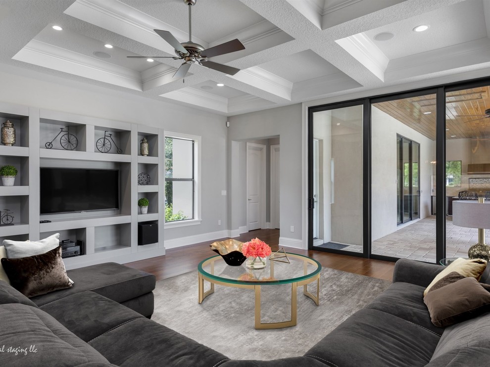Modelo de sala de estar abierta tradicional renovada grande con paredes blancas, suelo de madera oscura y pared multimedia