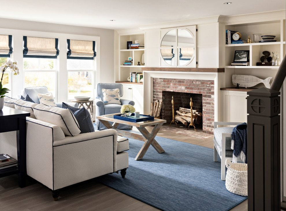 This is an example of a nautical living room in Boston with grey walls, medium hardwood flooring, a standard fireplace, a brick fireplace surround and brown floors.