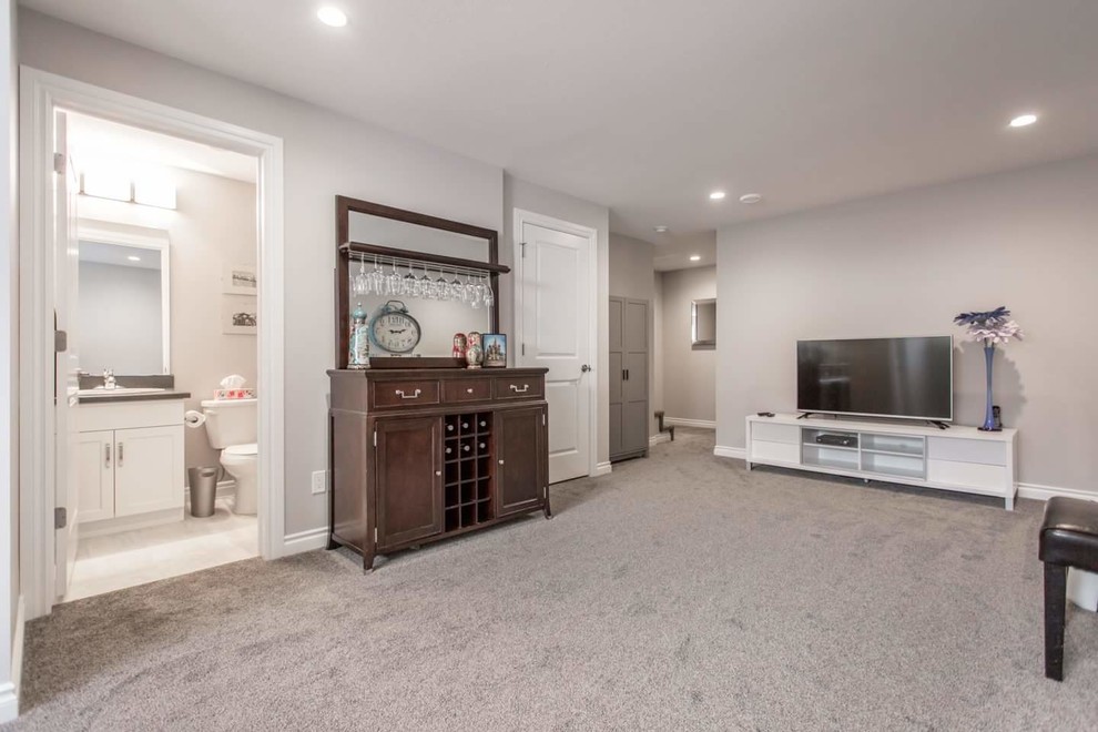 Modelo de sala de estar con barra de bar abierta clásica renovada de tamaño medio sin chimenea con paredes grises, moqueta, televisor independiente y suelo gris