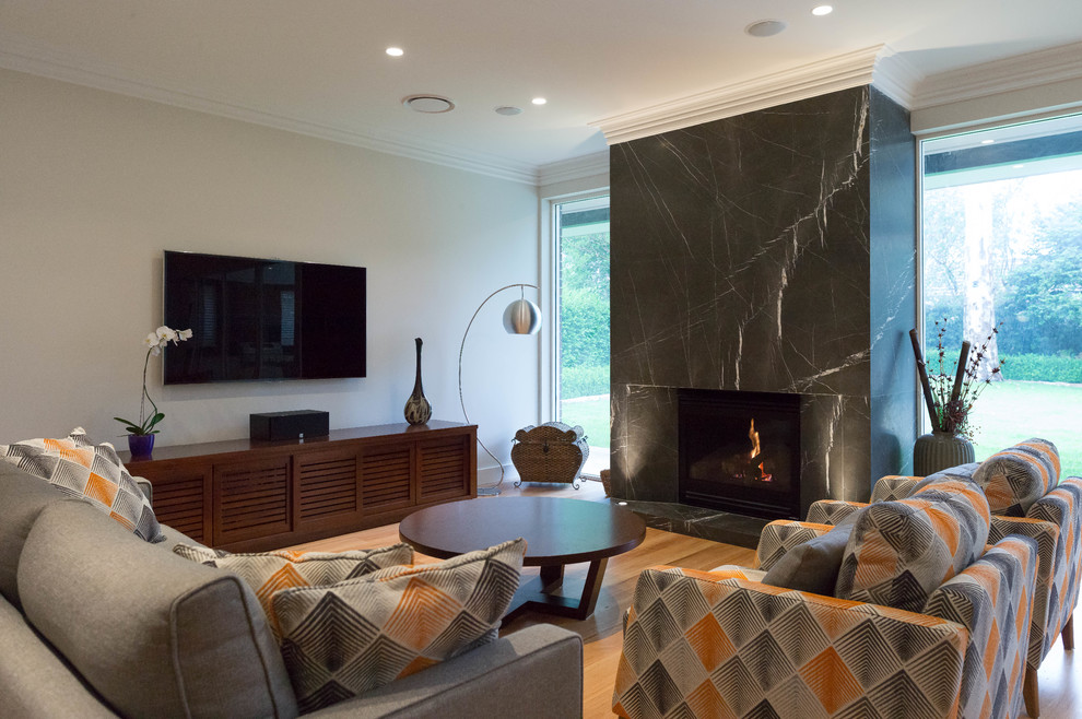Ejemplo de sala de estar cerrada clásica renovada con marco de chimenea de piedra y televisor colgado en la pared