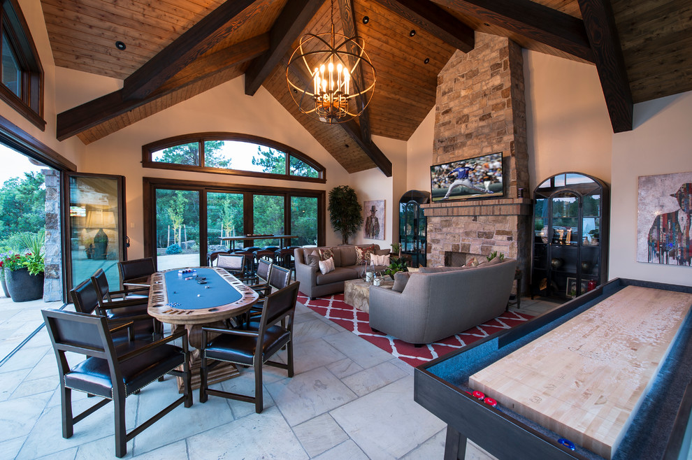 Photo of an expansive rustic open plan games room in Denver with a game room, a standard fireplace, a stone fireplace surround, a wall mounted tv, white walls, limestone flooring and white floors.
