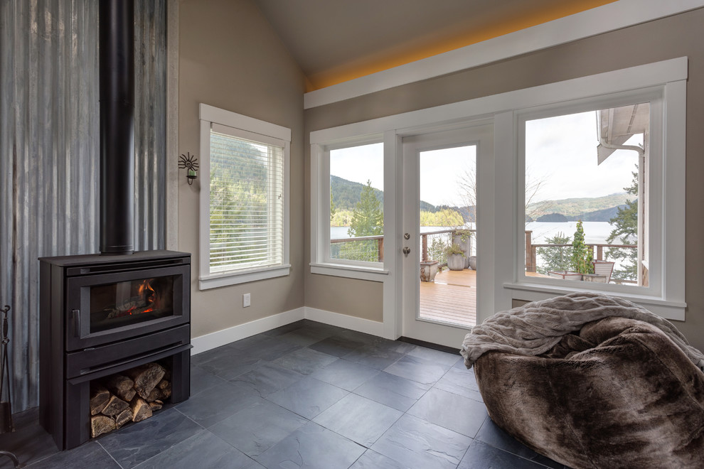 Inspiration for a coastal enclosed slate floor and black floor family room remodel in Seattle with beige walls, a wood stove and a metal fireplace