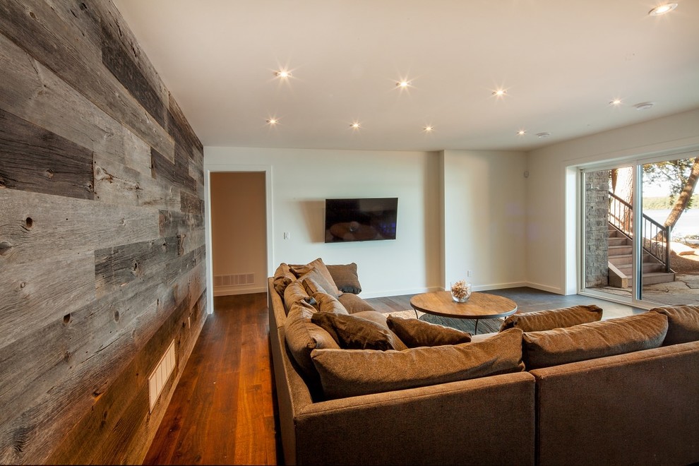 This is an example of a large rustic open plan games room in Toronto with a game room, white walls, dark hardwood flooring, a wall mounted tv and brown floors.