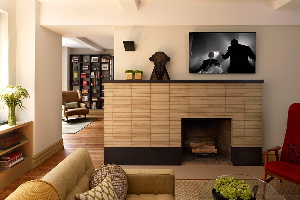 ニューヨークにあるお手頃価格の中くらいなコンテンポラリースタイルのおしゃれな独立型ファミリールーム (白い壁、無垢フローリング、標準型暖炉、壁掛け型テレビ、木材の暖炉まわり) の写真