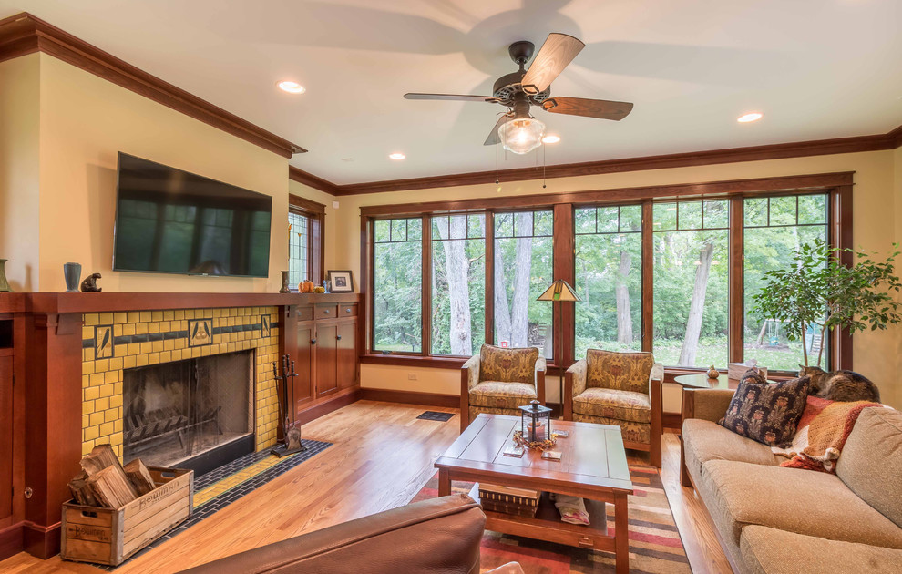 Photo of a medium sized classic open plan games room in Chicago with beige walls, light hardwood flooring, a standard fireplace, a tiled fireplace surround, a wall mounted tv, brown floors, a chimney breast, a wallpapered ceiling and wallpapered walls.