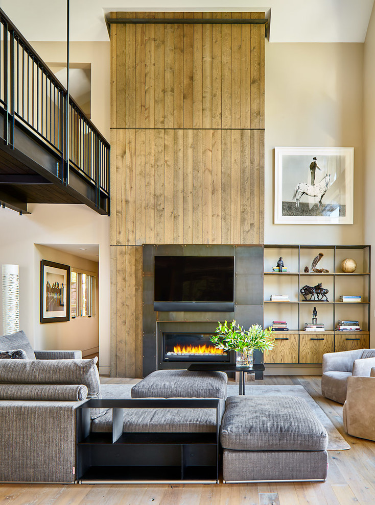 Diseño de sala de estar abierta rural extra grande con suelo de madera clara, chimenea lineal, marco de chimenea de metal, televisor colgado en la pared y paredes beige