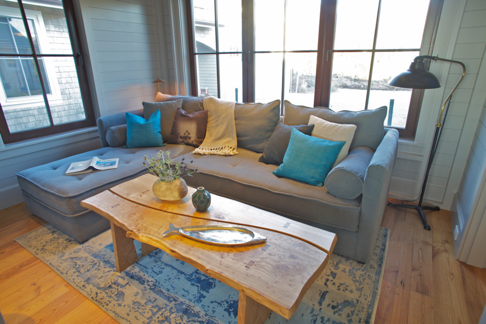 Diseño de sala de estar con biblioteca cerrada marinera con paredes azules, suelo de madera en tonos medios y pared multimedia
