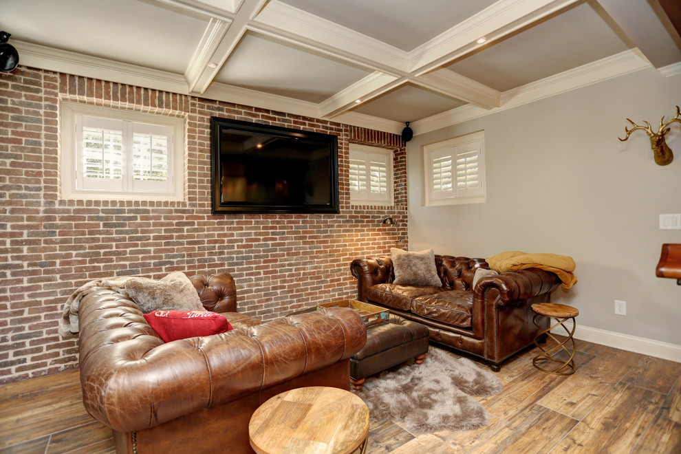 Ejemplo de sala de estar con barra de bar abierta clásica pequeña con paredes grises, suelo de baldosas de porcelana, pared multimedia, suelo marrón y marco de chimenea de ladrillo