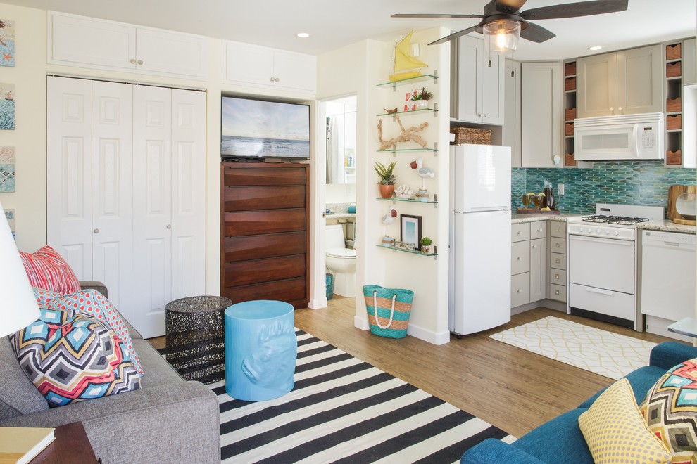 Offenes, Kleines Maritimes Wohnzimmer mit weißer Wandfarbe, Vinylboden, TV-Wand und braunem Boden in San Diego