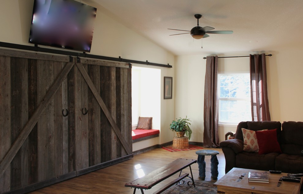 Foto di un ampio soggiorno country aperto con pareti bianche, pavimento in laminato e TV a parete
