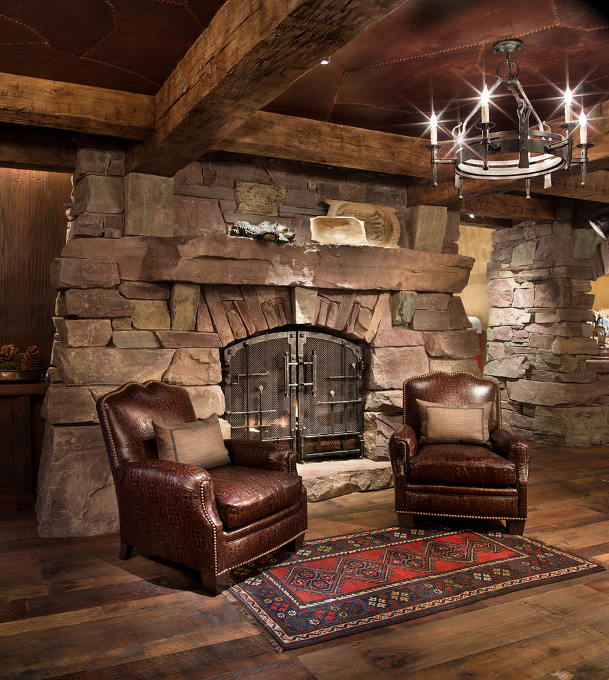 他の地域にあるラスティックスタイルのおしゃれな独立型ファミリールーム (無垢フローリング、標準型暖炉、石材の暖炉まわり、茶色い床) の写真