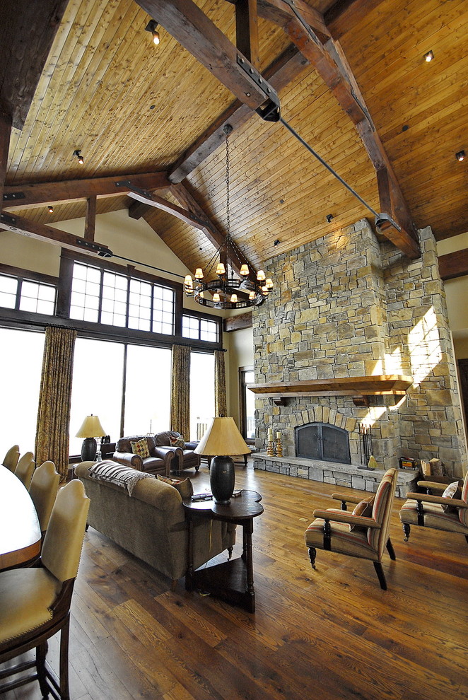 Inspiration pour une salle de séjour traditionnelle avec un mur beige, un sol en bois brun, une cheminée standard, un manteau de cheminée en pierre et aucun téléviseur.