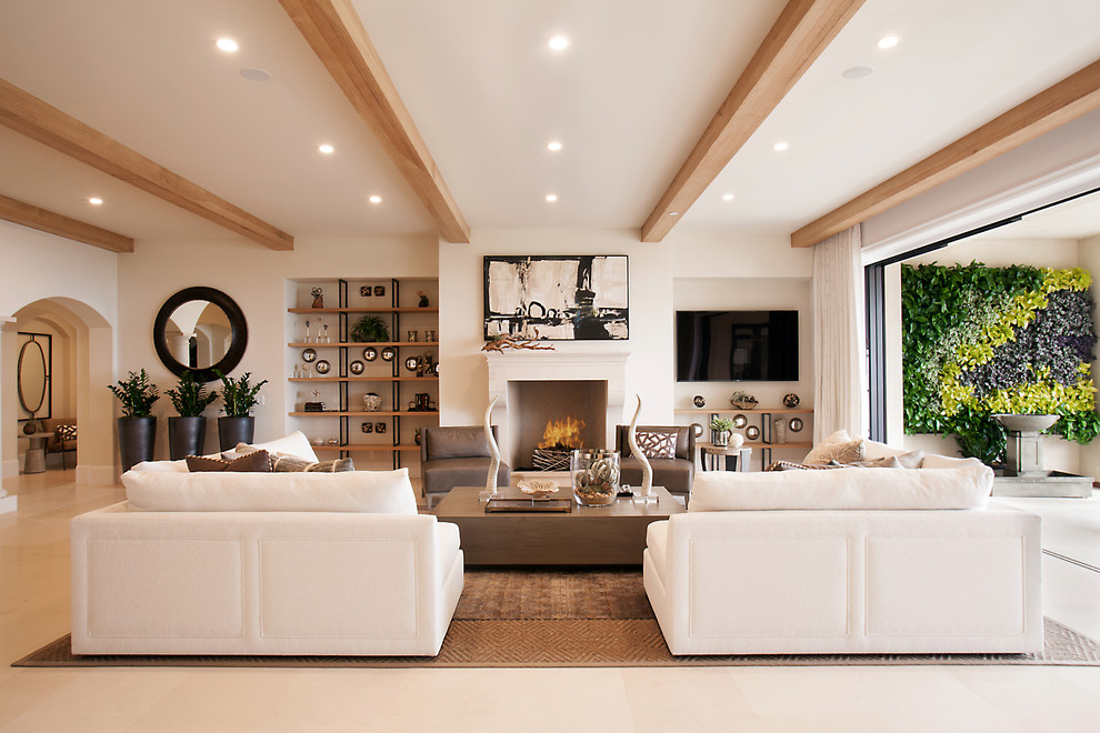 Offenes Mediterranes Wohnzimmer mit weißer Wandfarbe, Kalkstein, TV-Wand, Kamin und beigem Boden in Orange County