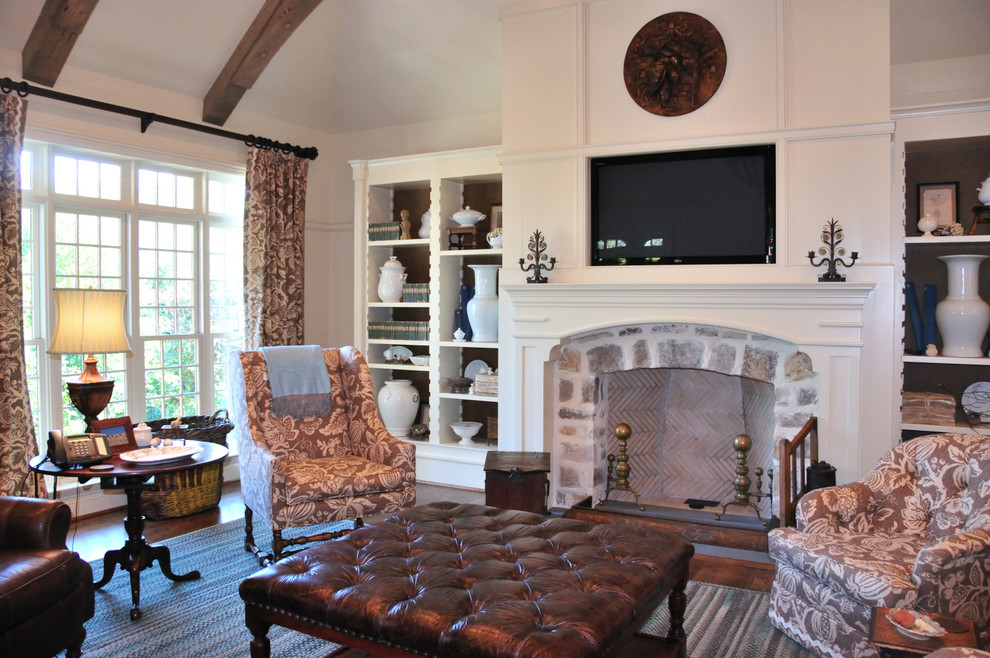 Example of a mid-sized classic enclosed dark wood floor and brown floor family room design in Birmingham with beige walls, a standard fireplace, a stone fireplace and a concealed tv
