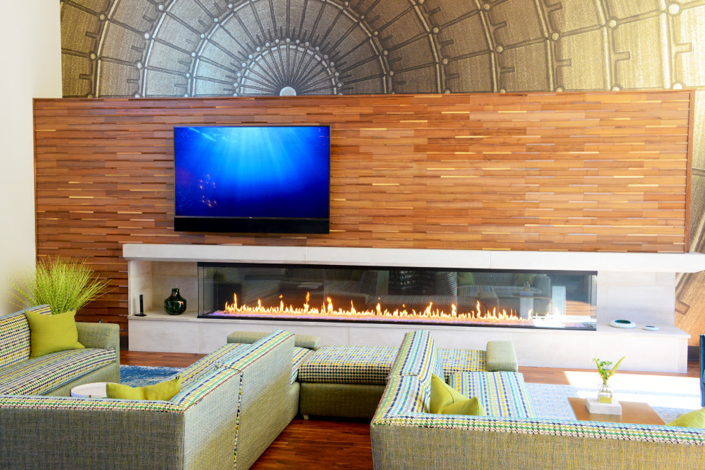 Immagine di un ampio soggiorno moderno aperto con pareti multicolore, pavimento in legno massello medio, camino sospeso, TV a parete, pavimento marrone e travi a vista