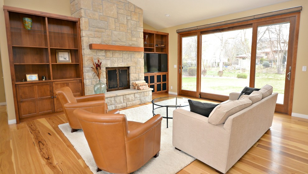 Diseño de sala de estar de estilo americano de tamaño medio con suelo de madera clara, todas las chimeneas, marco de chimenea de piedra y televisor independiente