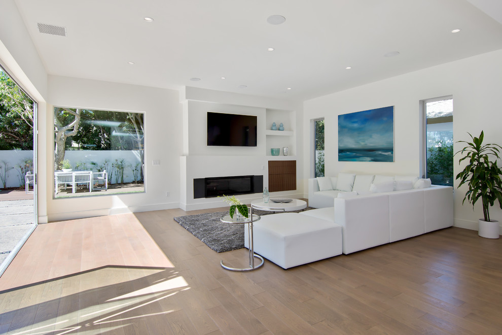 Offenes, Großes Retro Wohnzimmer mit weißer Wandfarbe, hellem Holzboden, TV-Wand, verputzter Kaminumrandung und Gaskamin in Los Angeles