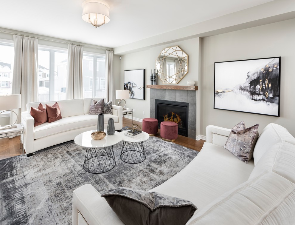 Inspiration for a large classic open plan games room in Ottawa with grey walls, medium hardwood flooring, a standard fireplace, a tiled fireplace surround and brown floors.