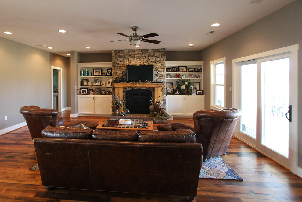 Imagen de sala de estar tradicional grande con paredes beige, suelo de madera en tonos medios, todas las chimeneas, marco de chimenea de piedra y televisor colgado en la pared