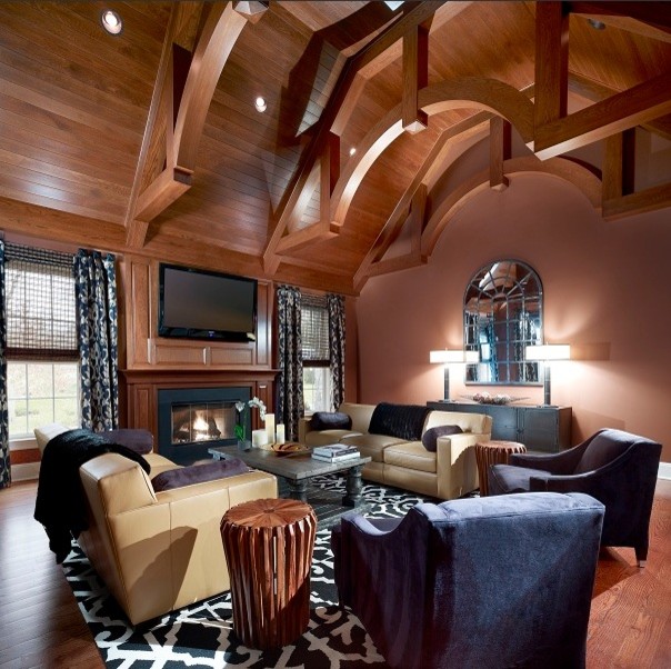 Cette photo montre une grande salle de séjour éclectique avec un sol en bois brun, une cheminée standard, un manteau de cheminée en pierre, un téléviseur fixé au mur et un mur rose.