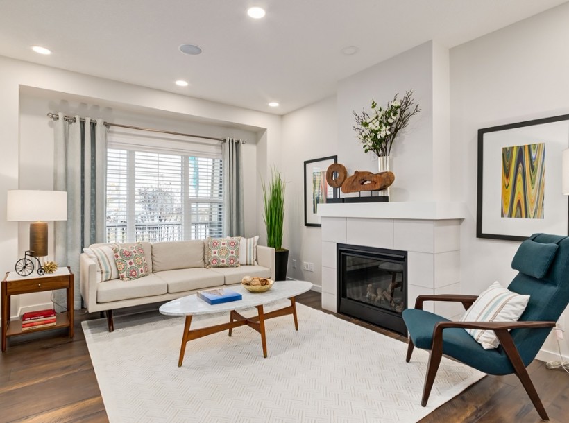 Photo of a medium sized contemporary open plan games room in Calgary with white walls, laminate floors, a standard fireplace, a tiled fireplace surround and brown floors.