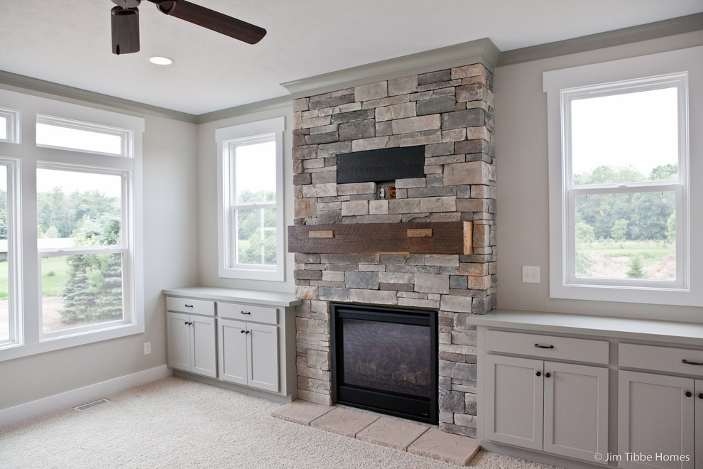 This is an example of a classic games room in Grand Rapids with grey walls, carpet, a standard fireplace, a stone fireplace surround and a built-in media unit.