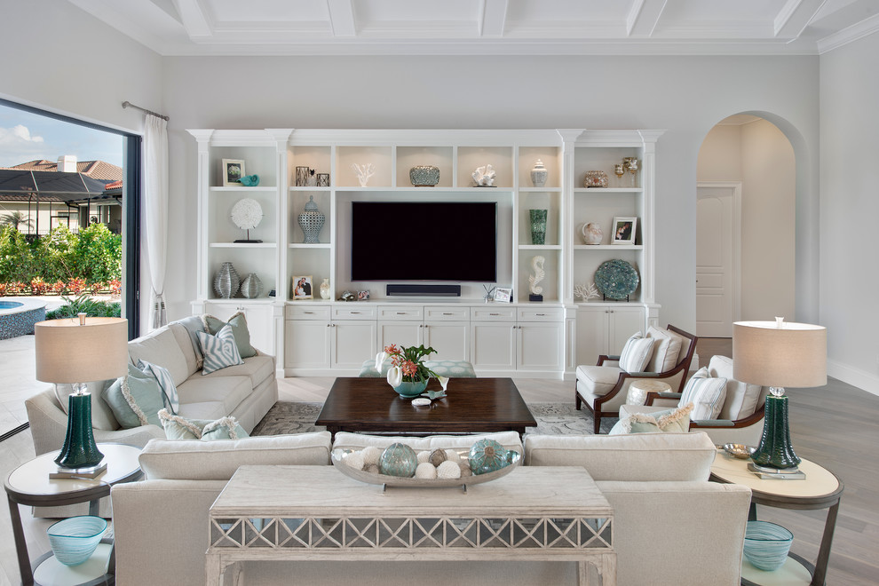 Imagen de sala de estar abierta clásica grande sin chimenea con suelo de madera clara y televisor colgado en la pared
