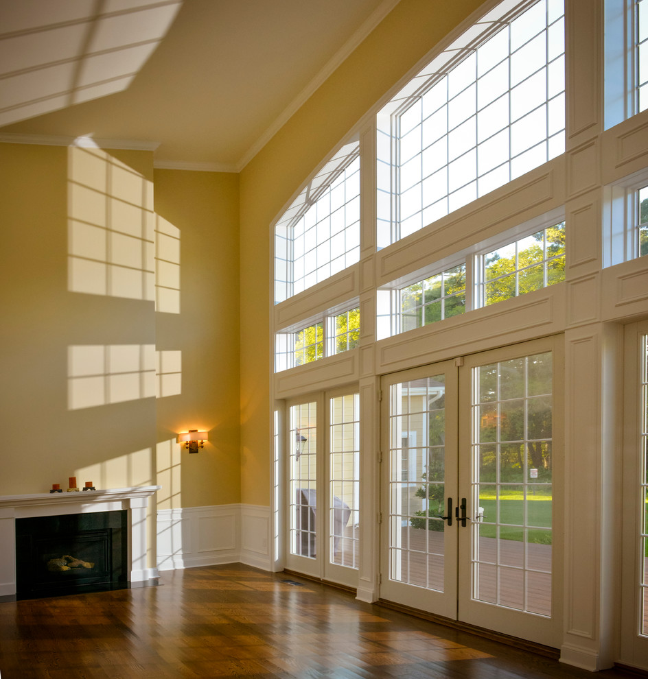 На фото: гостиная комната в классическом стиле с паркетным полом среднего тона, стандартным камином и фасадом камина из дерева