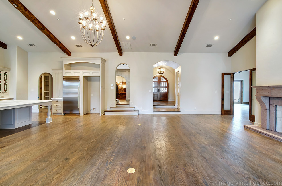 Offener Mediterraner Hobbyraum mit braunem Holzboden, Kamin und Kaminumrandung aus Stein in Dallas