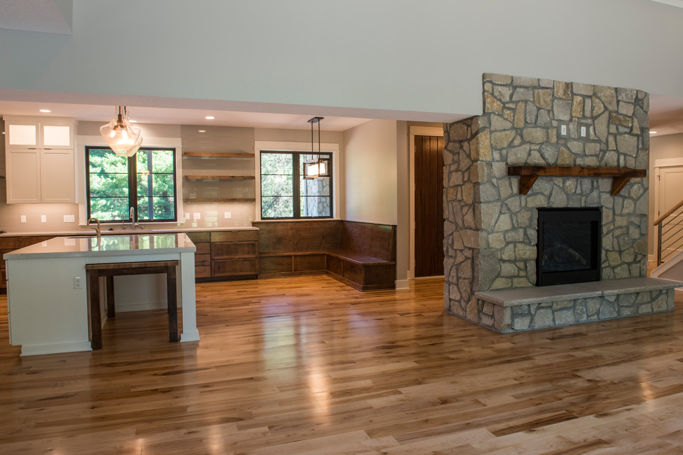 Exemple d'une grande salle de séjour nature ouverte avec un mur beige, un sol en bois brun, une cheminée standard et un manteau de cheminée en pierre.