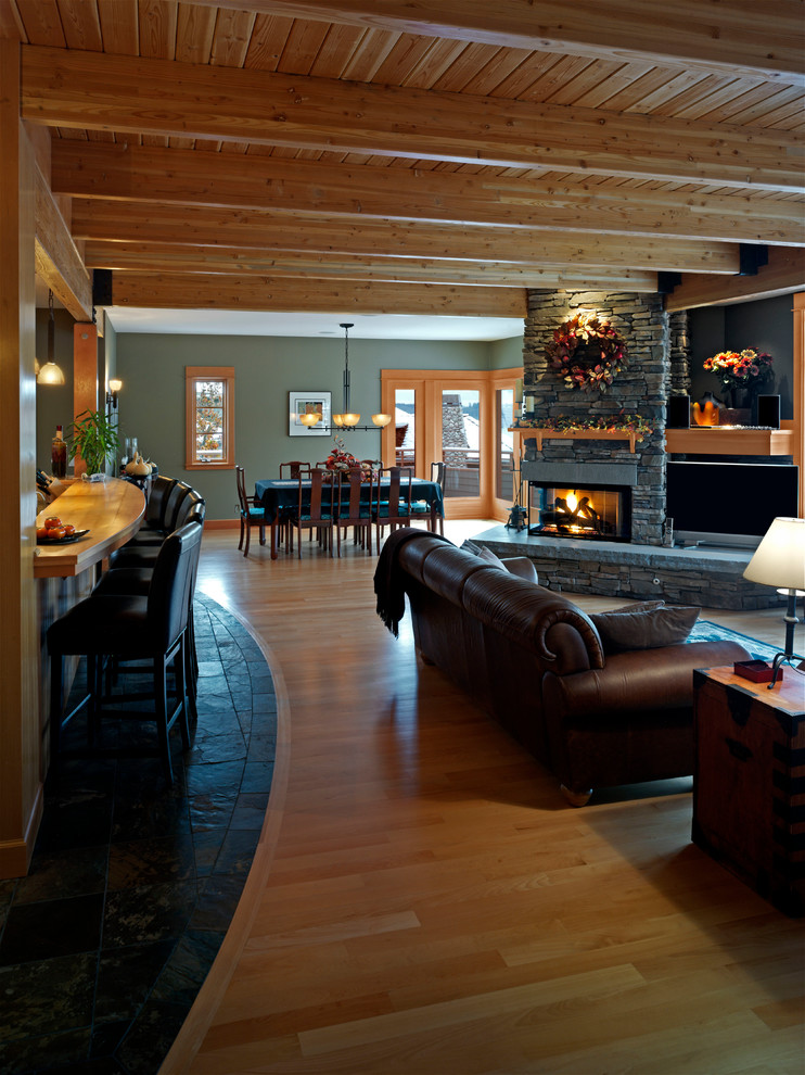 Cette image montre une salle de séjour design de taille moyenne et ouverte avec une cheminée d'angle, un manteau de cheminée en pierre, un bar de salon, un mur vert, parquet clair et un téléviseur fixé au mur.