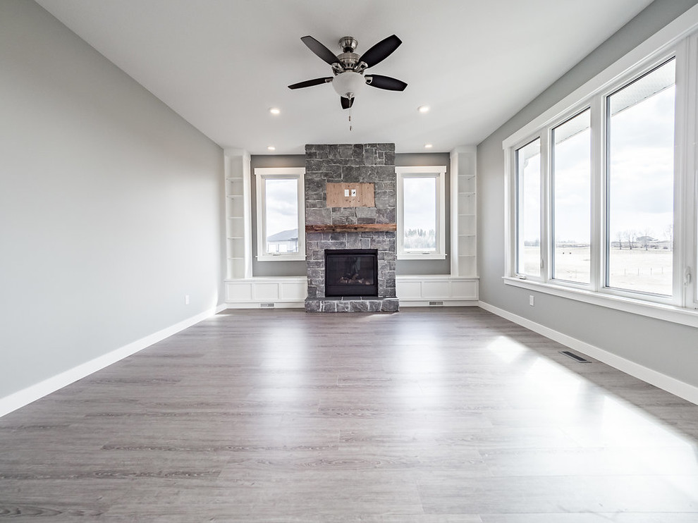 Mittelgroßes, Abgetrenntes Country Wohnzimmer mit grauer Wandfarbe, Vinylboden, Kamin, Kaminumrandung aus Backstein und grauem Boden in Calgary