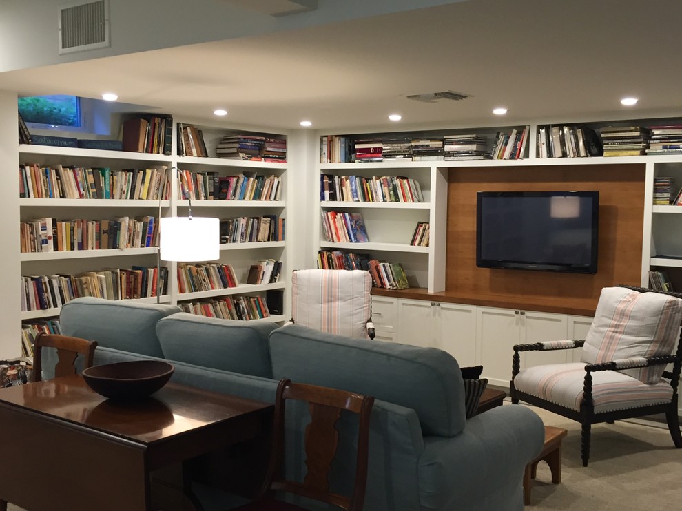 Cette photo montre une grande salle de séjour bord de mer ouverte avec une bibliothèque ou un coin lecture, un mur beige et un téléviseur fixé au mur.