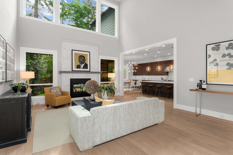 Großes, Offenes Modernes Wohnzimmer mit grauer Wandfarbe, braunem Holzboden, Tunnelkamin, gefliester Kaminumrandung und braunem Boden in Seattle