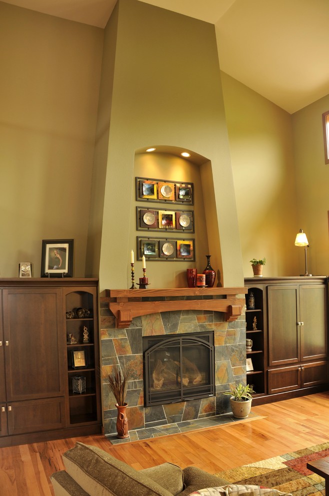 Offenes Modernes Wohnzimmer mit grüner Wandfarbe, braunem Holzboden, Kamin, gefliester Kaminumrandung und verstecktem TV in Sonstige