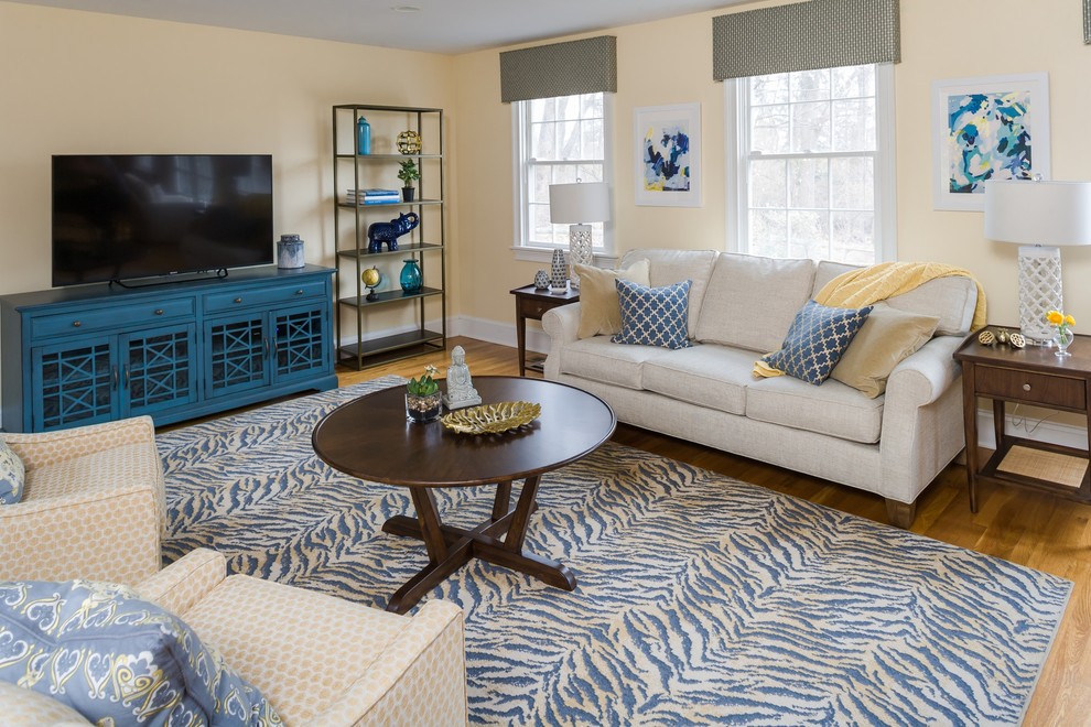 Foto de sala de estar clásica renovada grande con paredes amarillas, televisor independiente y suelo de madera clara