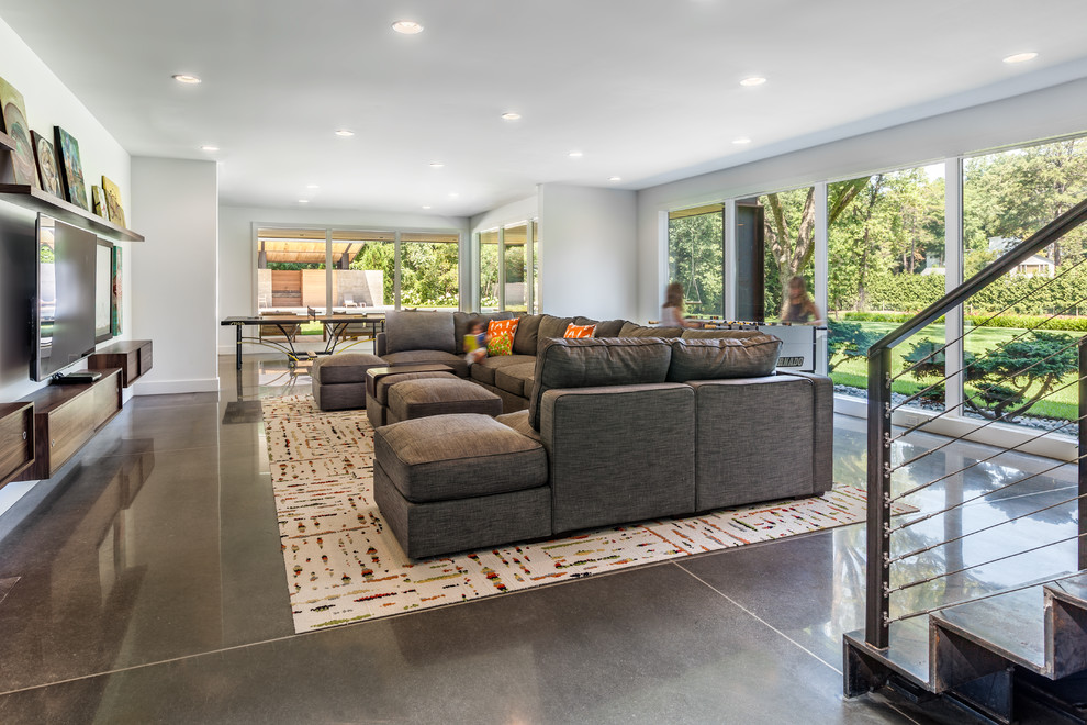 Family room - large contemporary open concept concrete floor family room idea in Charleston with white walls and a wall-mounted tv