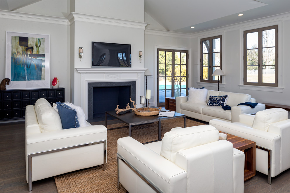 Imagen de sala de estar abierta clásica grande con paredes blancas, suelo de madera en tonos medios, todas las chimeneas, marco de chimenea de madera y televisor colgado en la pared