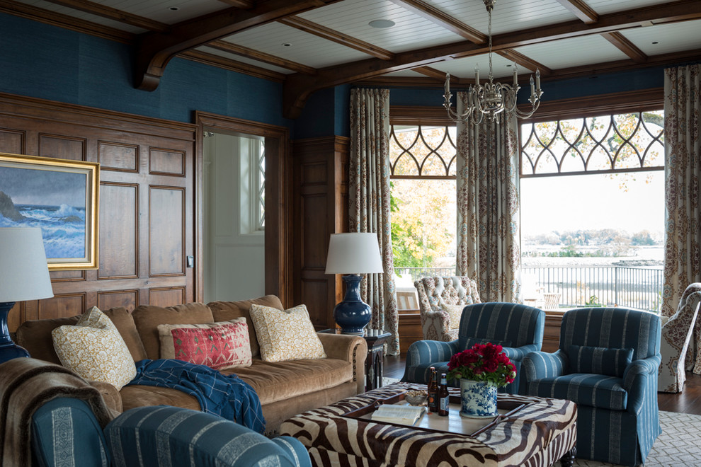 На фото: большая изолированная гостиная комната в классическом стиле с с книжными шкафами и полками, синими стенами, паркетным полом среднего тона, стандартным камином, фасадом камина из дерева и коричневым полом без телевизора