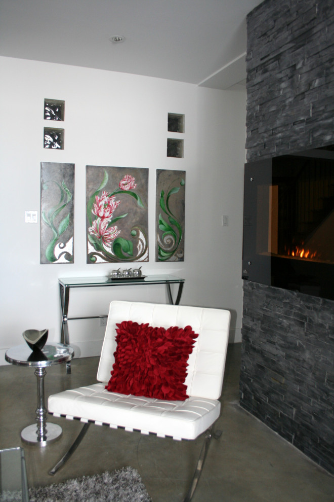 Foto de sala de estar abierta contemporánea de tamaño medio con paredes blancas, suelo de cemento, chimeneas suspendidas, marco de chimenea de piedra, televisor independiente y suelo gris