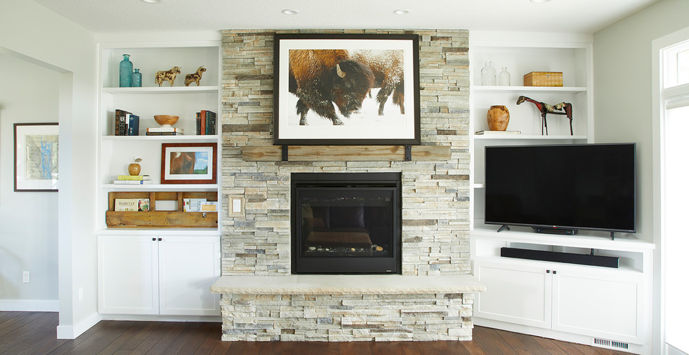 Cette photo montre une petite salle de séjour nature ouverte avec un mur gris, parquet foncé, une cheminée standard, un manteau de cheminée en pierre, un téléviseur d'angle et un sol marron.