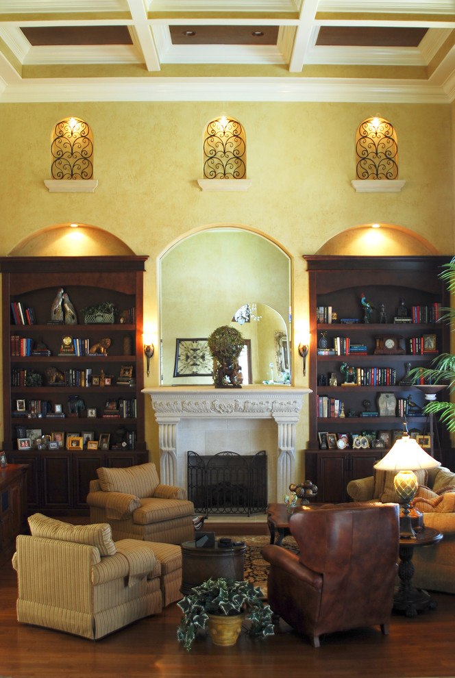 Family room library - large traditional open concept medium tone wood floor family room library idea in Orlando with yellow walls, a standard fireplace, a plaster fireplace and no tv