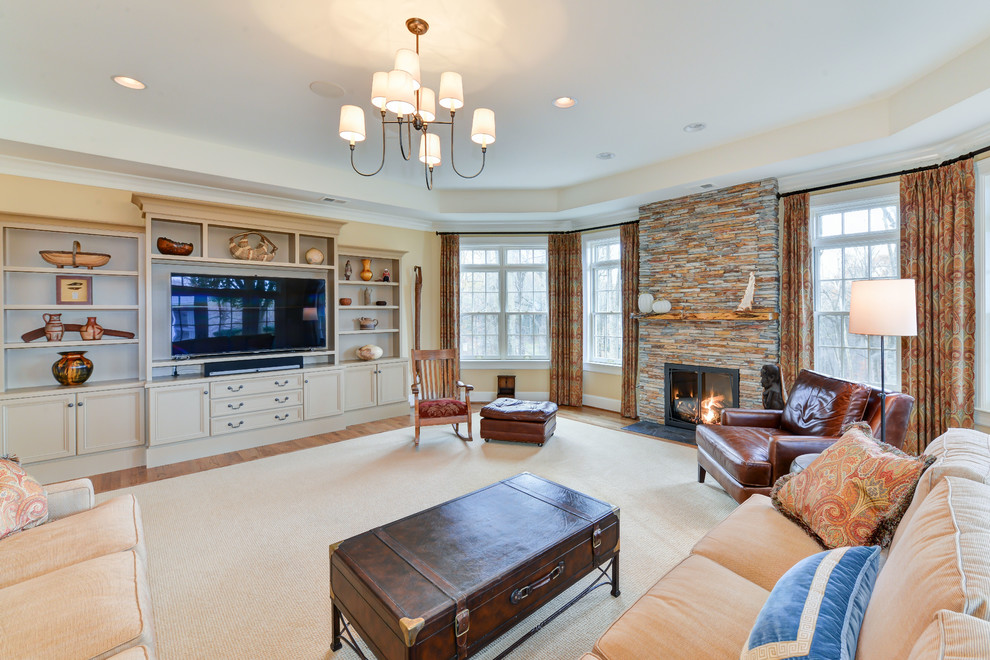 Example of a large classic open concept medium tone wood floor family room design with yellow walls, a standard fireplace, a media wall and a stone fireplace