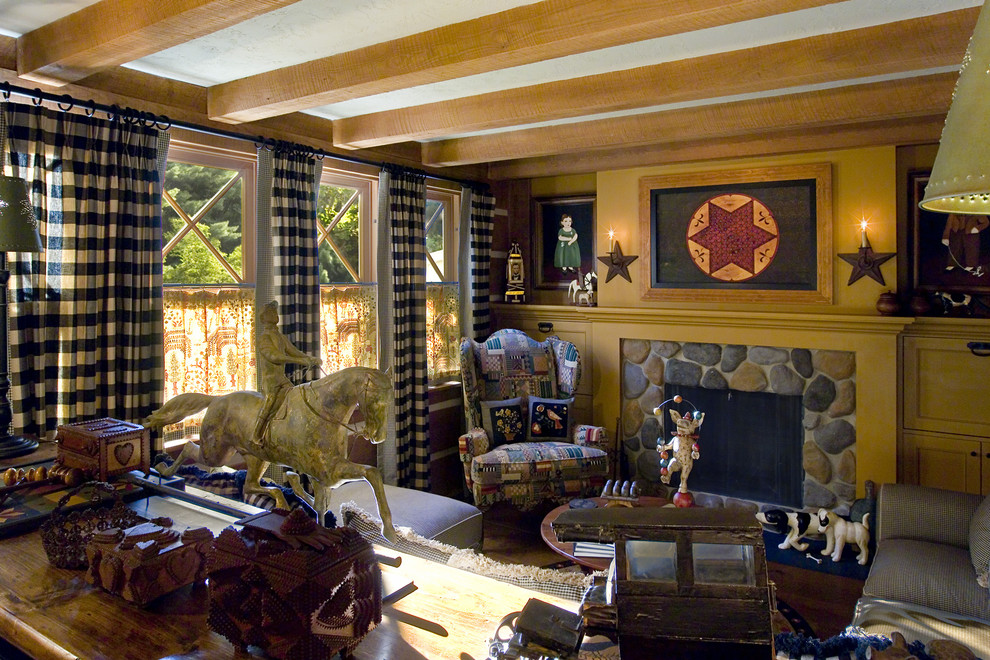 Cette image montre une salle de séjour bohème de taille moyenne et ouverte avec un mur jaune, un sol en bois brun, une cheminée standard, un manteau de cheminée en pierre, un téléviseur dissimulé et un sol marron.